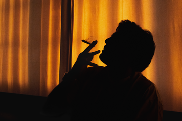 Silhouette of a person against a warm-toned curtain background